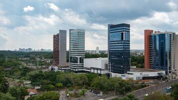 A cityscape with modern high-rise buildings, a shopping center, and a mix of greenery.