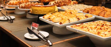 A buffet with various food items including pastries, bread, and desserts.