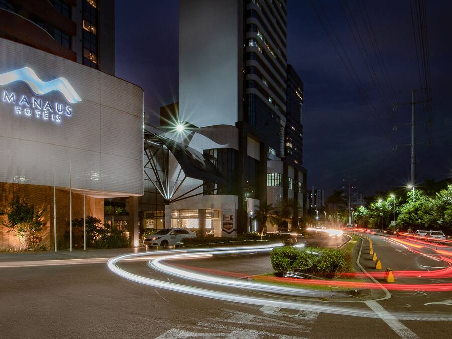 A modern hotel with a prominent sign, a curved glass facade, and a well-lit entrance.