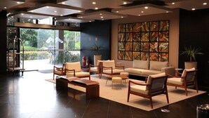 A modern lobby with a large seating area, a glass entrance, and a colorful abstract art piece on the wall. - Manaus Hotéis - Millennium (Manaus)