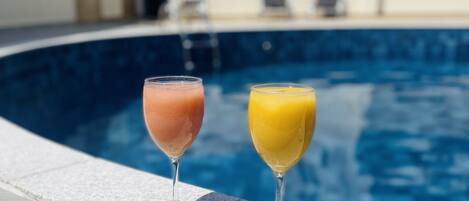 Una piscina con dos vasos de bebidas sobre el borde.