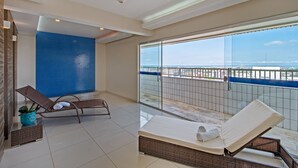 A balcony with a view of the city, two sun loungers, and a large window. - Hotel Adrianópolis All Suites (Manaus)