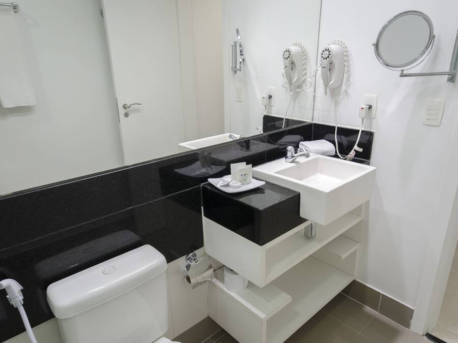 Un baño moderno con encimera negra, lavabo blanco y retrete.