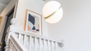 A staircase with white balusters and a white handrail, leading to a landing with a framed abstract painting.