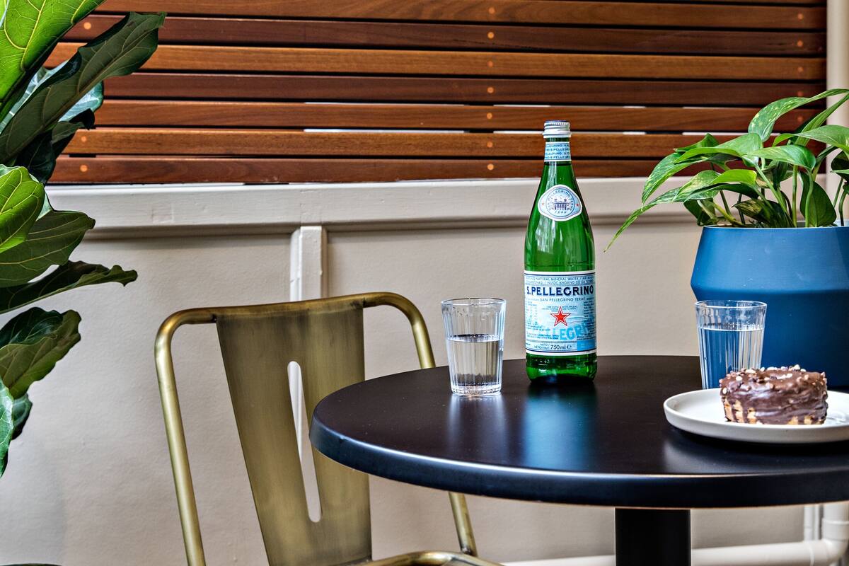 A round table with a bottle of Pellegrino water, a glass, and a plate with a pastry.