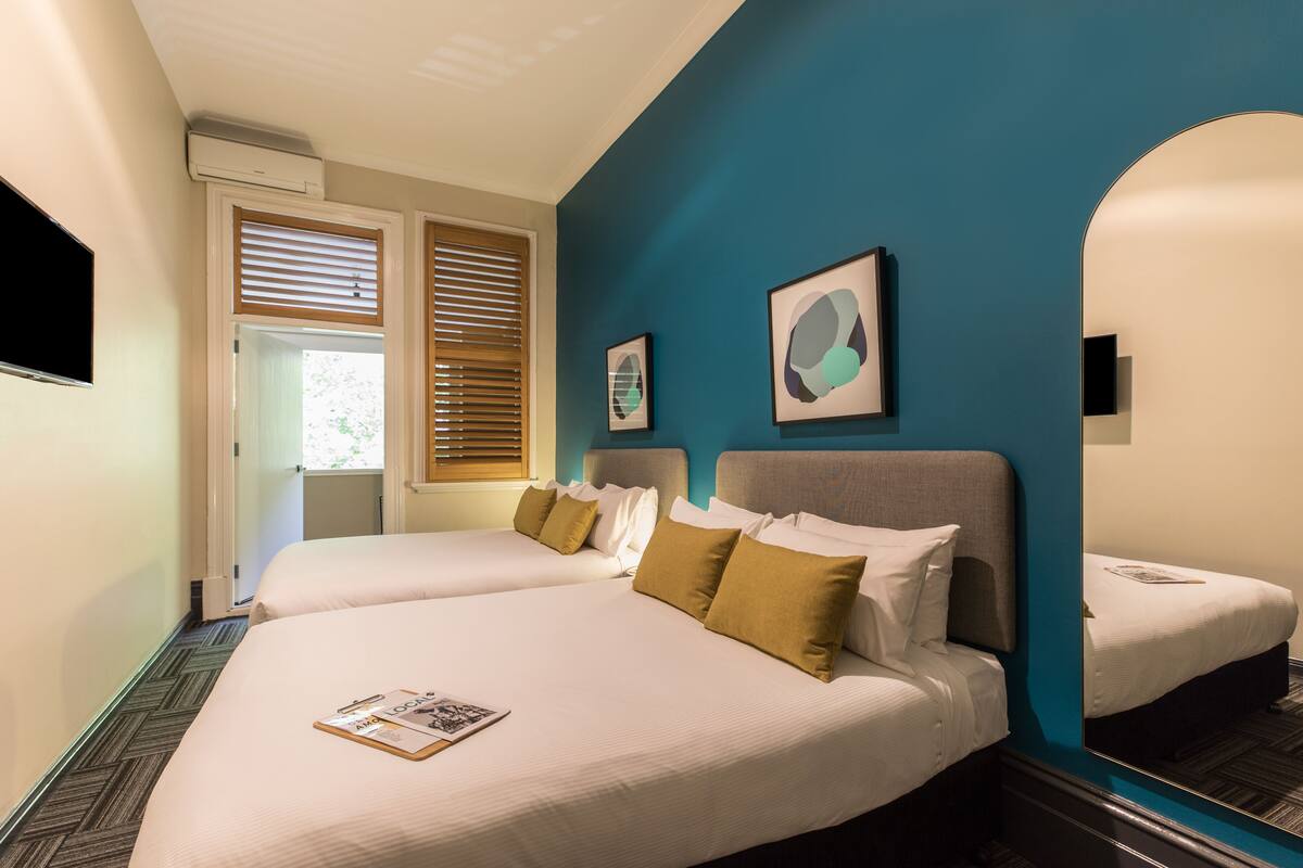 A hotel room with two beds, a large mirror, and artwork on the walls.