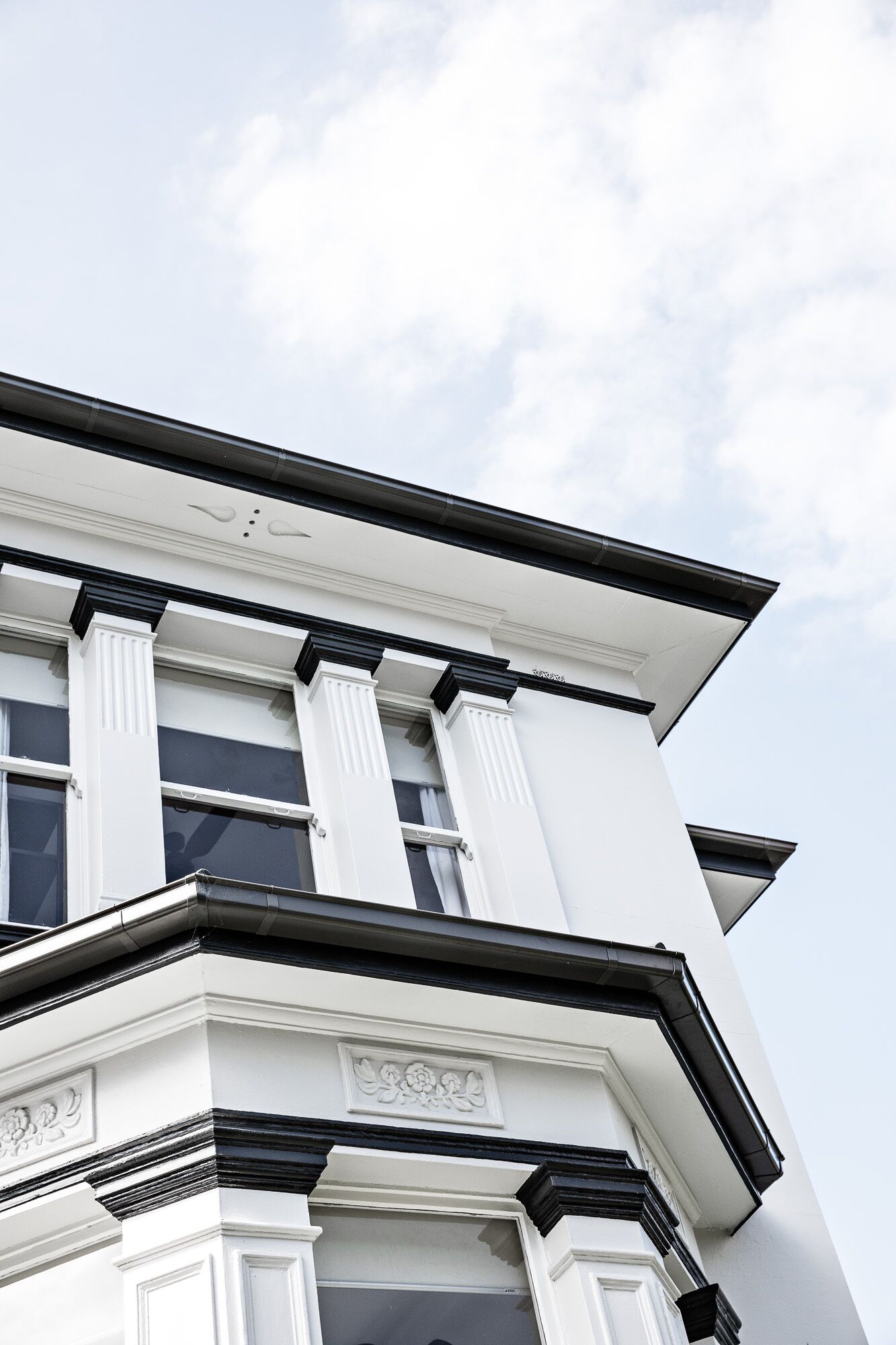 A corner of a building with white columns and a black roof.