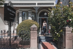 Entrada de un edificio con un letrero que dice "HIGH CROSS RANDWICK" y un seto bien cuidado.
