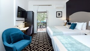 Ein Hotelzimmer mit einem großen Bett, einem blauen Sessel, einem an der Wand montierten Fernseher und Blick auf den Balkon.