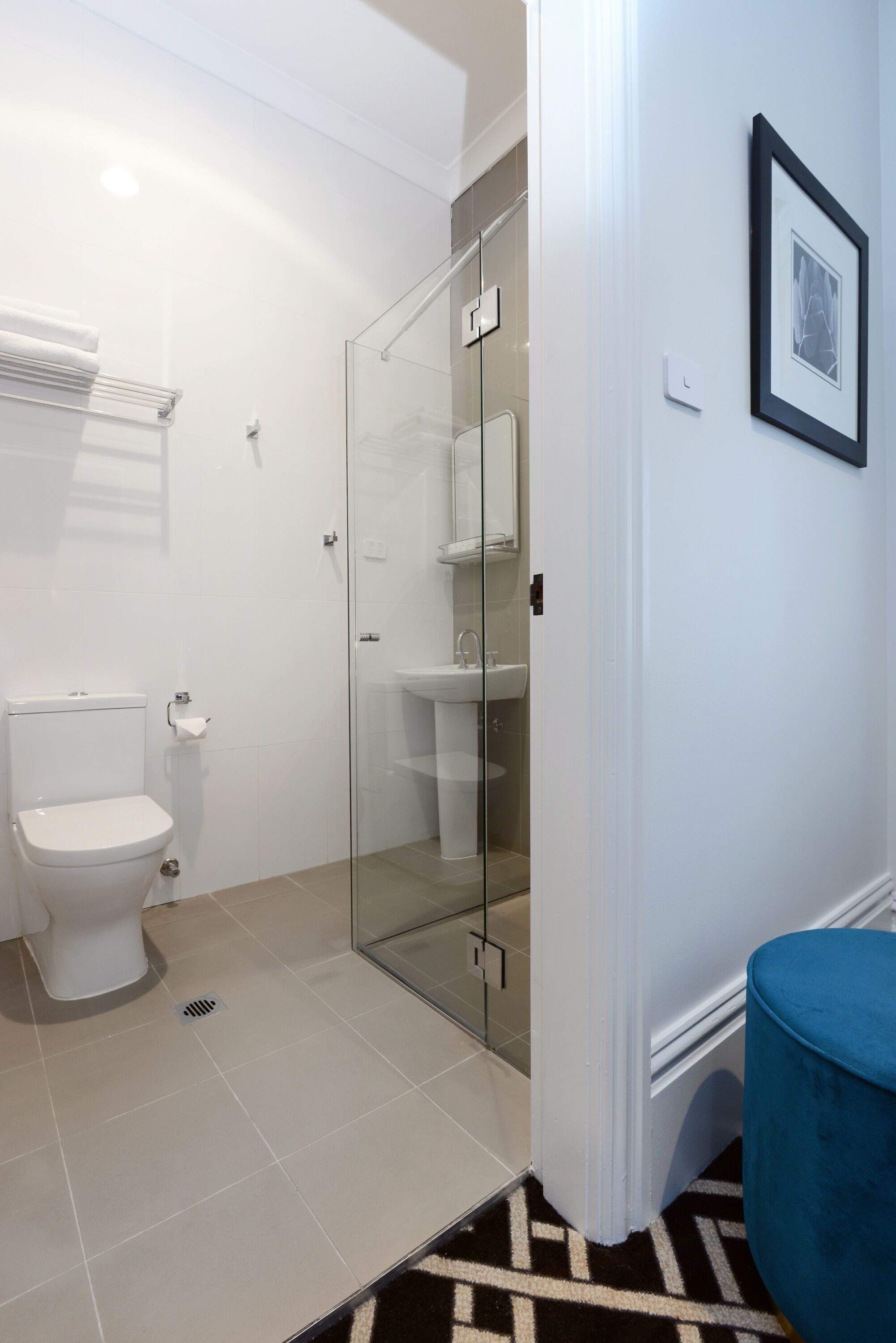 A modern bathroom with a glass shower enclosure, a white toilet, and a sink.