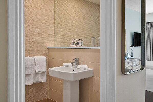 Un baño moderno con un lavamanos blanco, un espejo y un perchero para toallas.