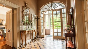 A hallway with a patterned floor, a mirror, a console table with a vase, and a door leading to a bright room. - Summerhill House Hotel (Enniskerry)