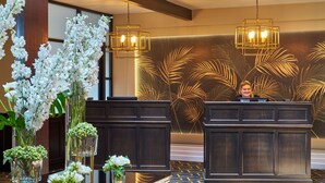 A reception area with two dark wooden reception desks, a large floral wall mural, and a chandelier above. - Summerhill House Hotel (Enniskerry)