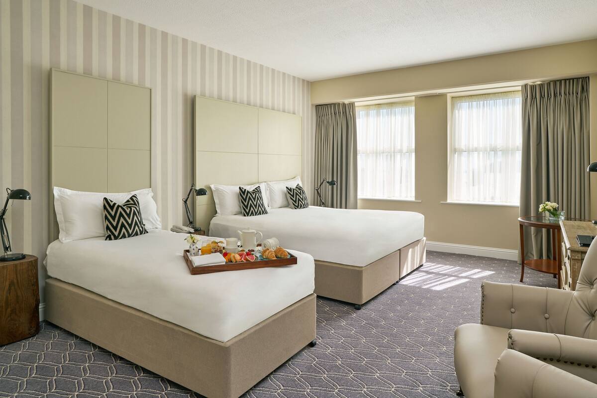 A hotel room with two beds, a sitting area, and a television.