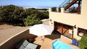 A rooftop pool area with a lounge chair and umbrella, a pool, and a view of the ocean. - Lavender Manor Guest Lodge (Hermanus)