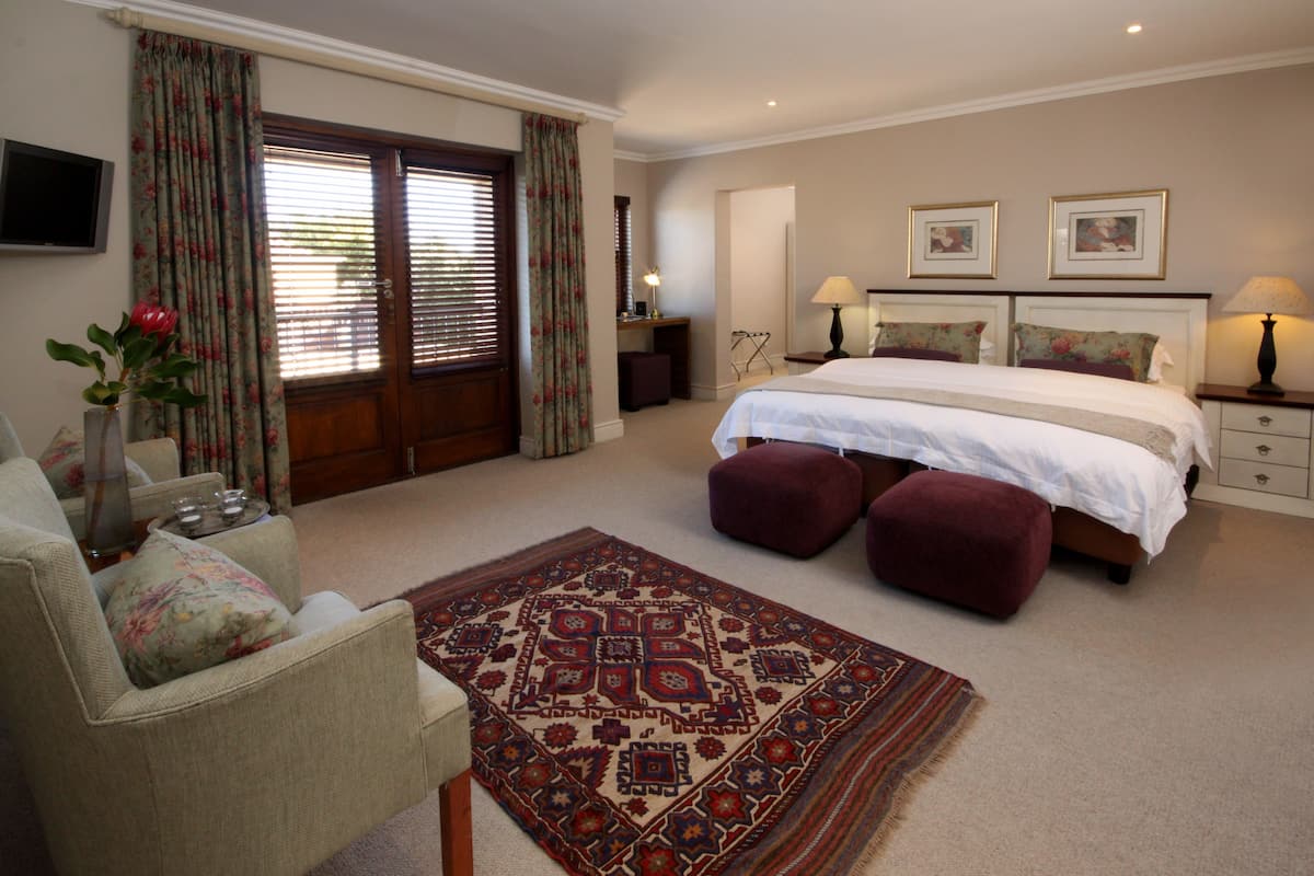Une chambre à coucher avec un grand lit, deux tables de chevet, un bureau, une chaise, un téléviseur et un tapis à motifs.