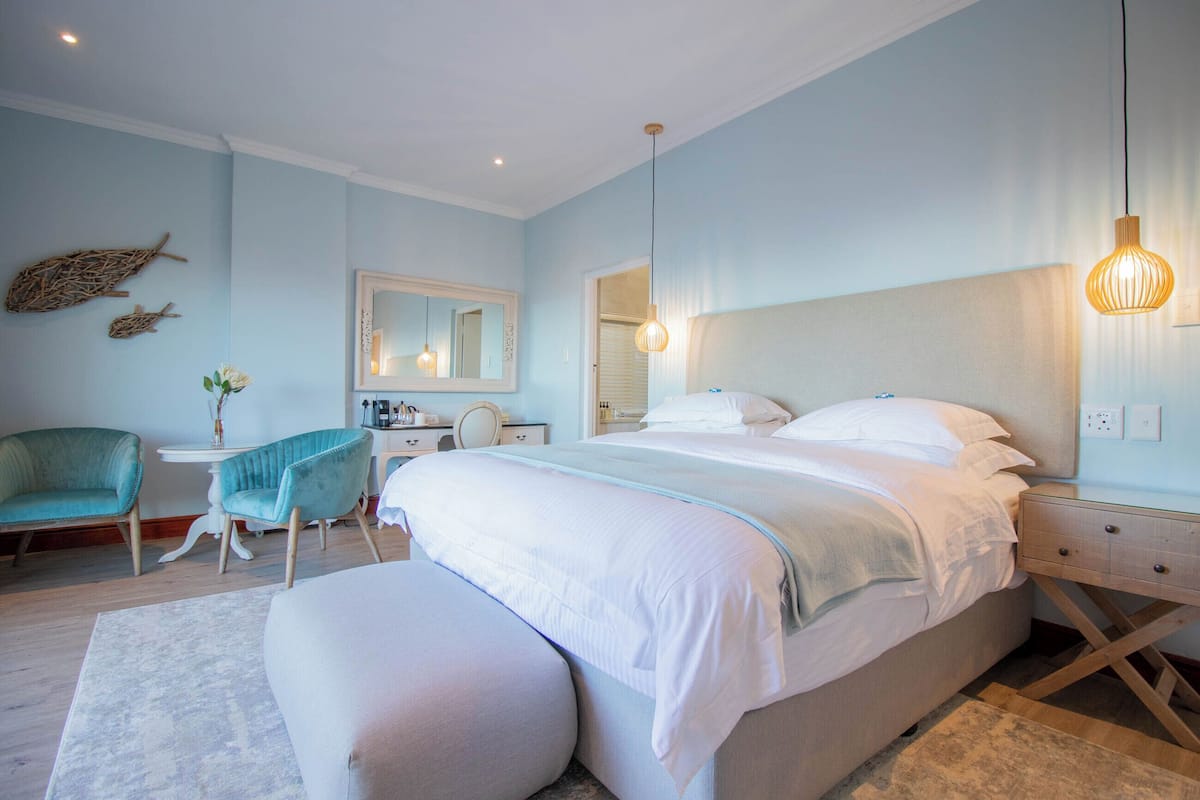 Une chambre à coucher avec un lit, une chaise, un bureau et un miroir.