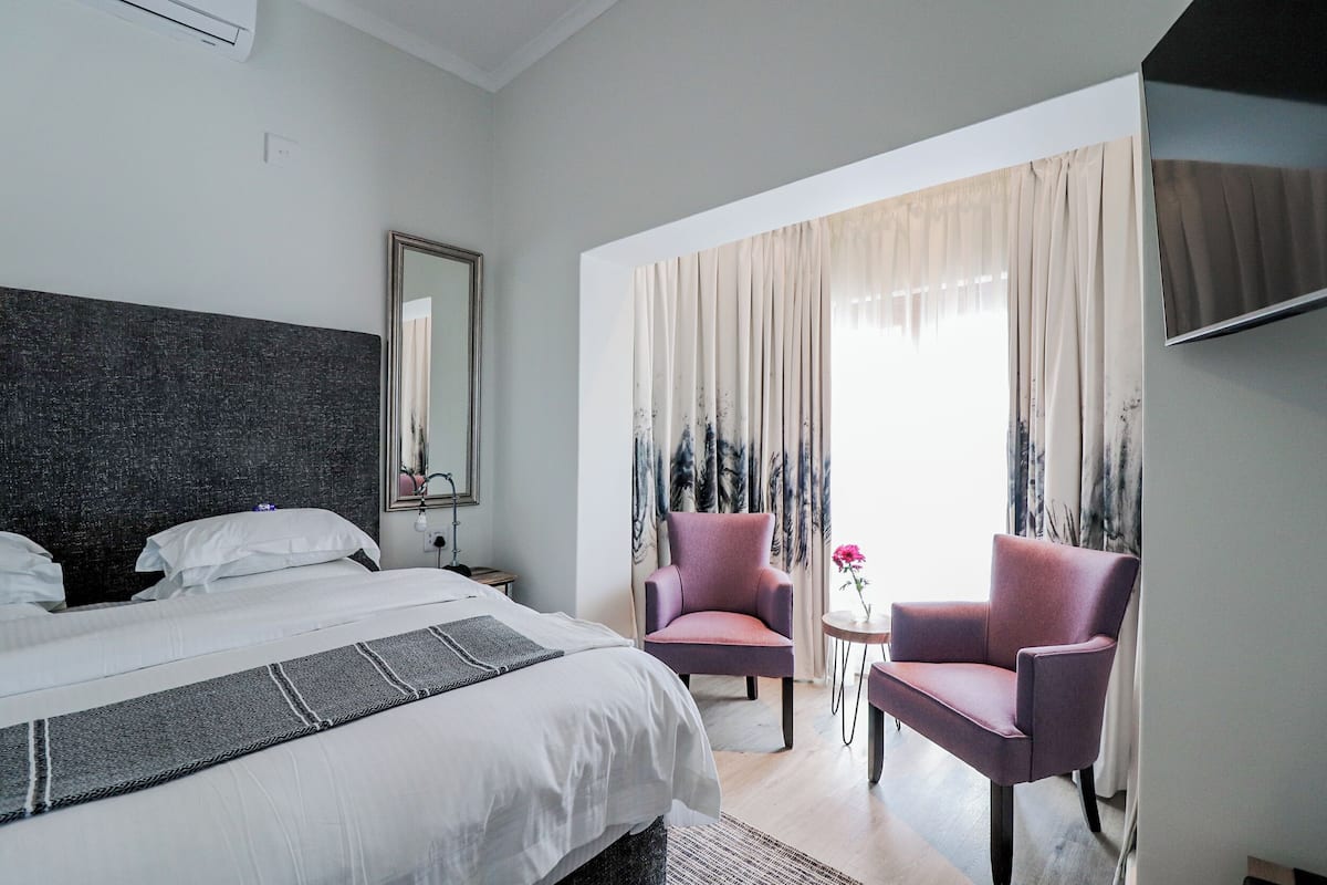 Une chambre d’hôtel avec un grand lit, deux chaises, une petite table et un téléviseur.
