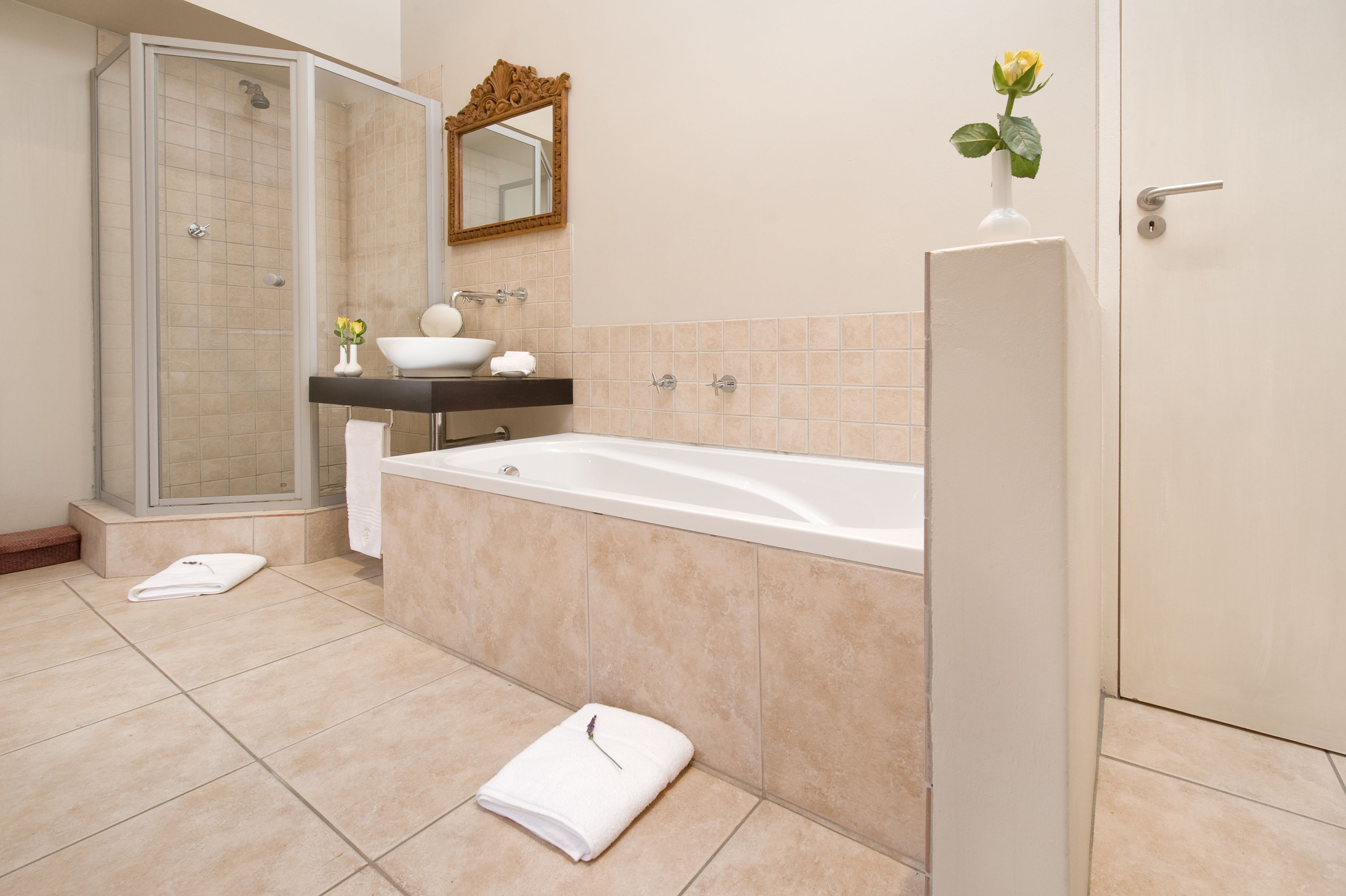 A modern bathroom with a walk-in shower, a bathtub, a vanity with a sink, and a mirror.