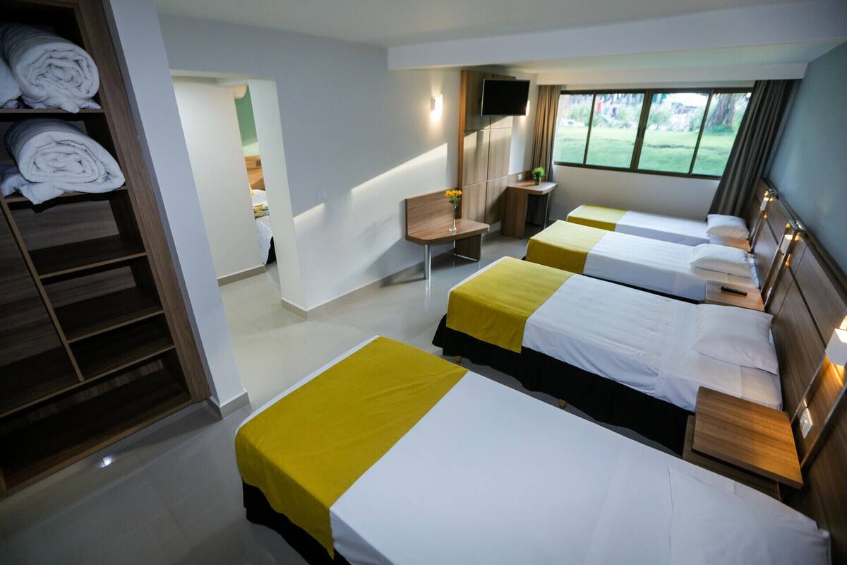 Ein Hotelzimmer mit zwei Betten, einem Fernseher, einem Schreibtisch und Blick ins Freie.