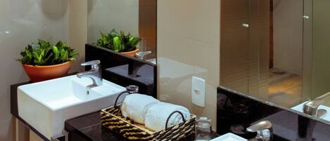 Un baño moderno con dos lavamanos, un espejo grande y luminarias colgantes.