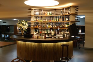 Enjoy a drink at the hotel's bar, featuring a curved countertop, wine cooler, and elegant decor.