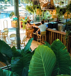 Enjoy dining with a marina view at this restaurant's outdoor seating area, featuring comfortable chairs and tables amidst lush greenery.