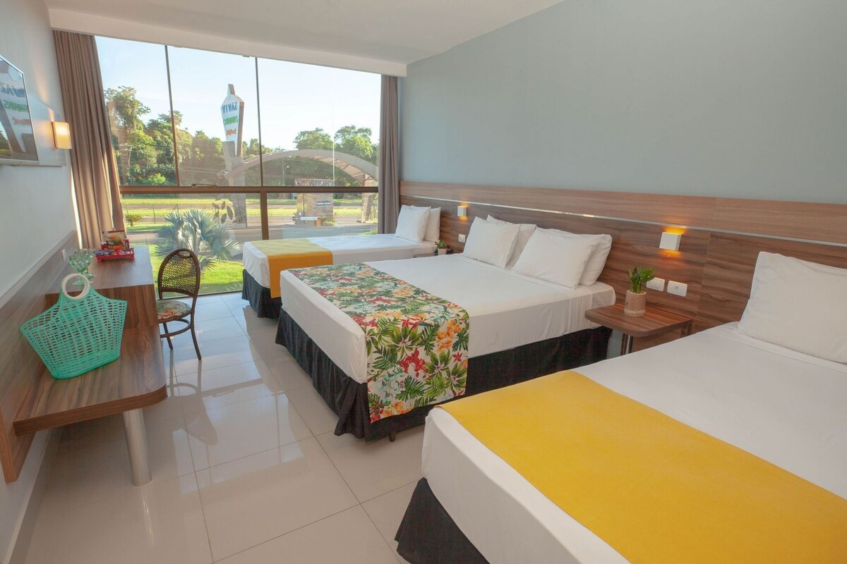 Una habitación de hotel con dos camas, un escritorio, una silla y vistas al exterior.
