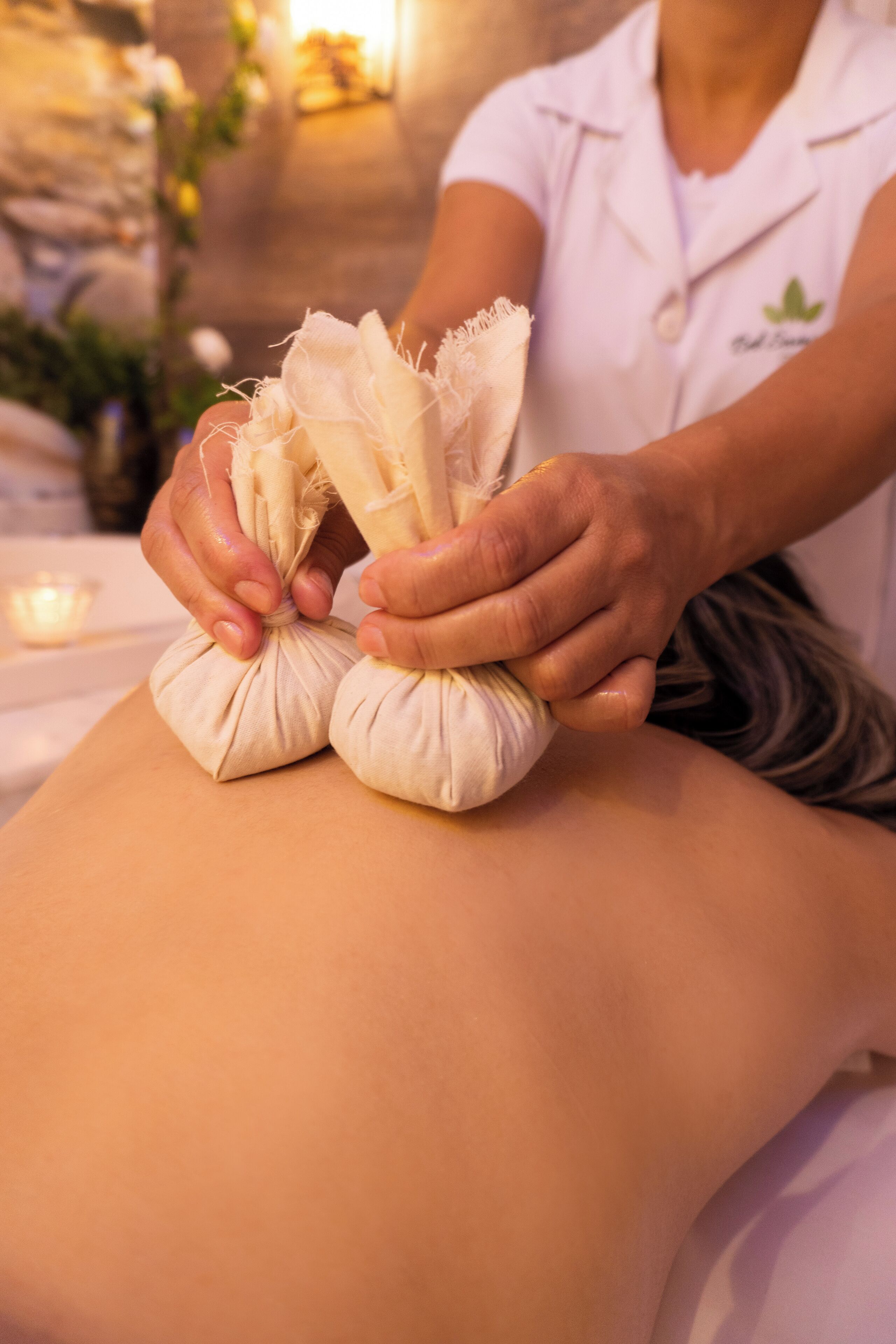 A massage therapist applying a treatment to a client's back using a towel and a cloth.