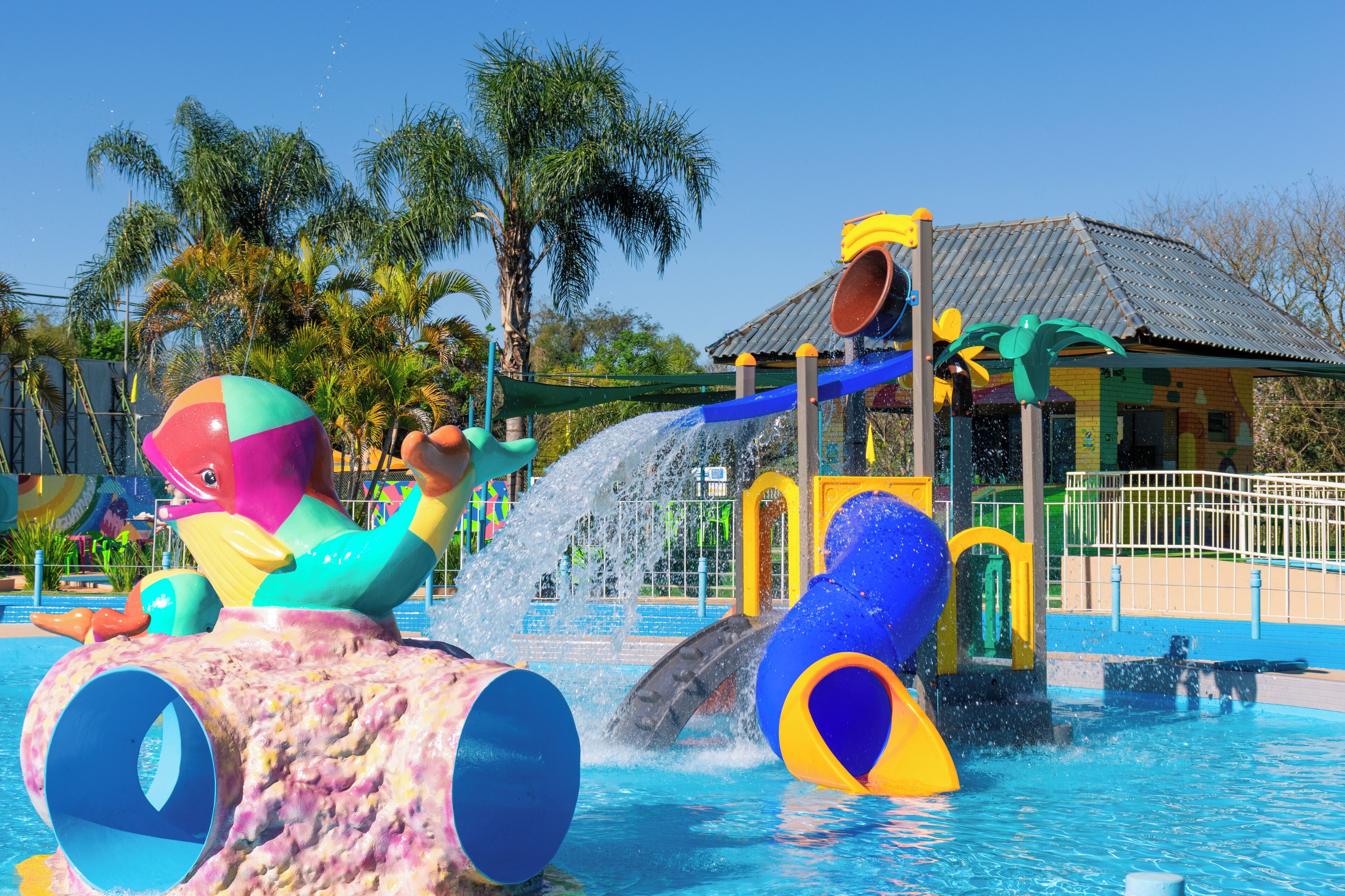 Un parque acuático con toboganes, estructuras de juego coloridas y una piscina.