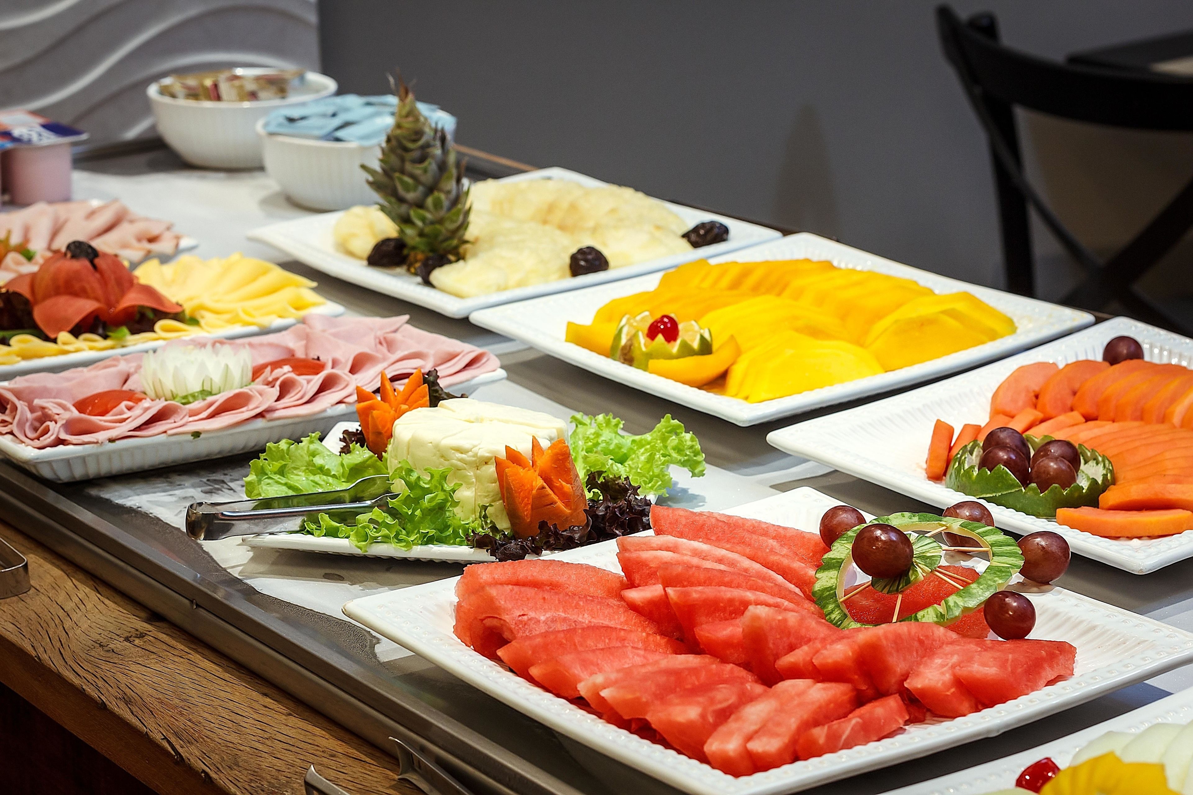A buffet with various food items including fruits, vegetables, and meats.