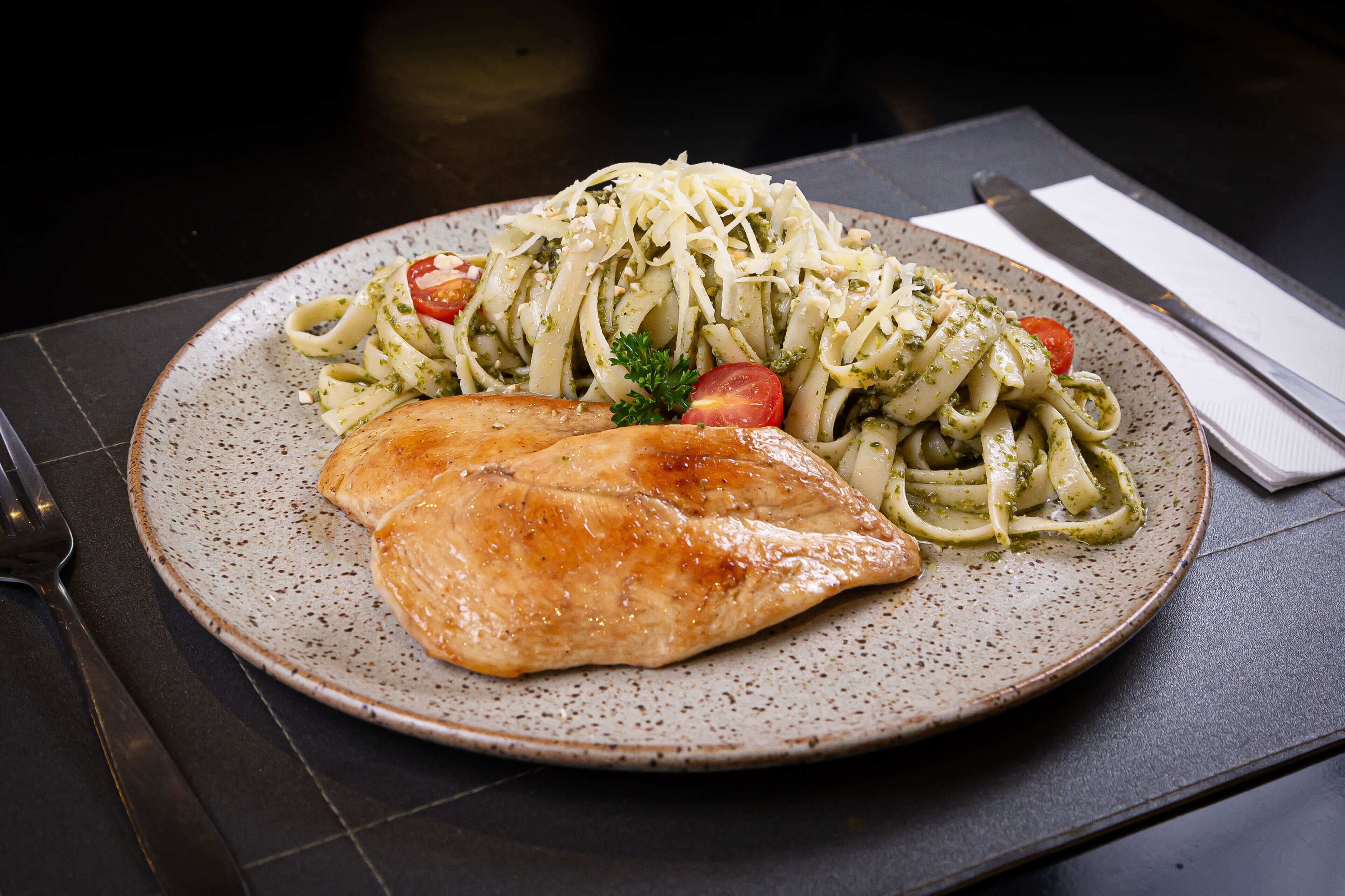 A plate of pasta with a piece of grilled chicken and cherry tomatoes.