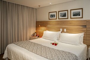 Habitación de hotel con una cama grande, cabecera de madera y tres cuadros enmarcados en la pared.
