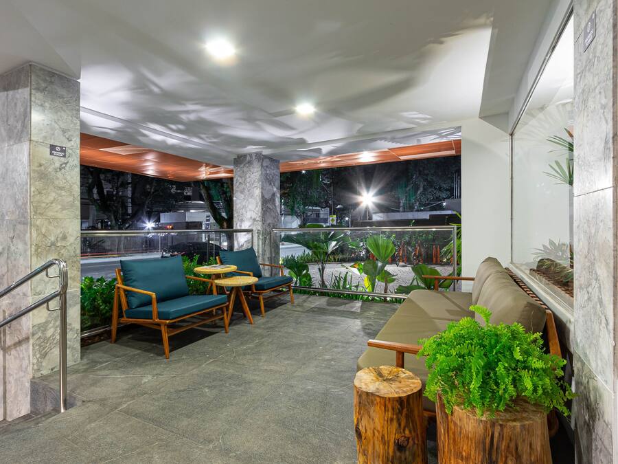Un área de estar interior moderna con suelo de piedra, mobiliario de madera y vistas a la calle.