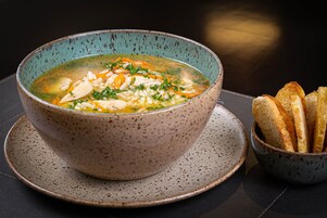 Un tazón de sopa con pan sobre un plato.