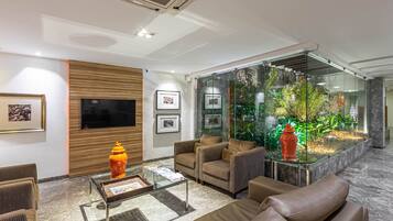 A modern lobby with a glass fish tank, comfortable seating, and framed artwork on the walls.