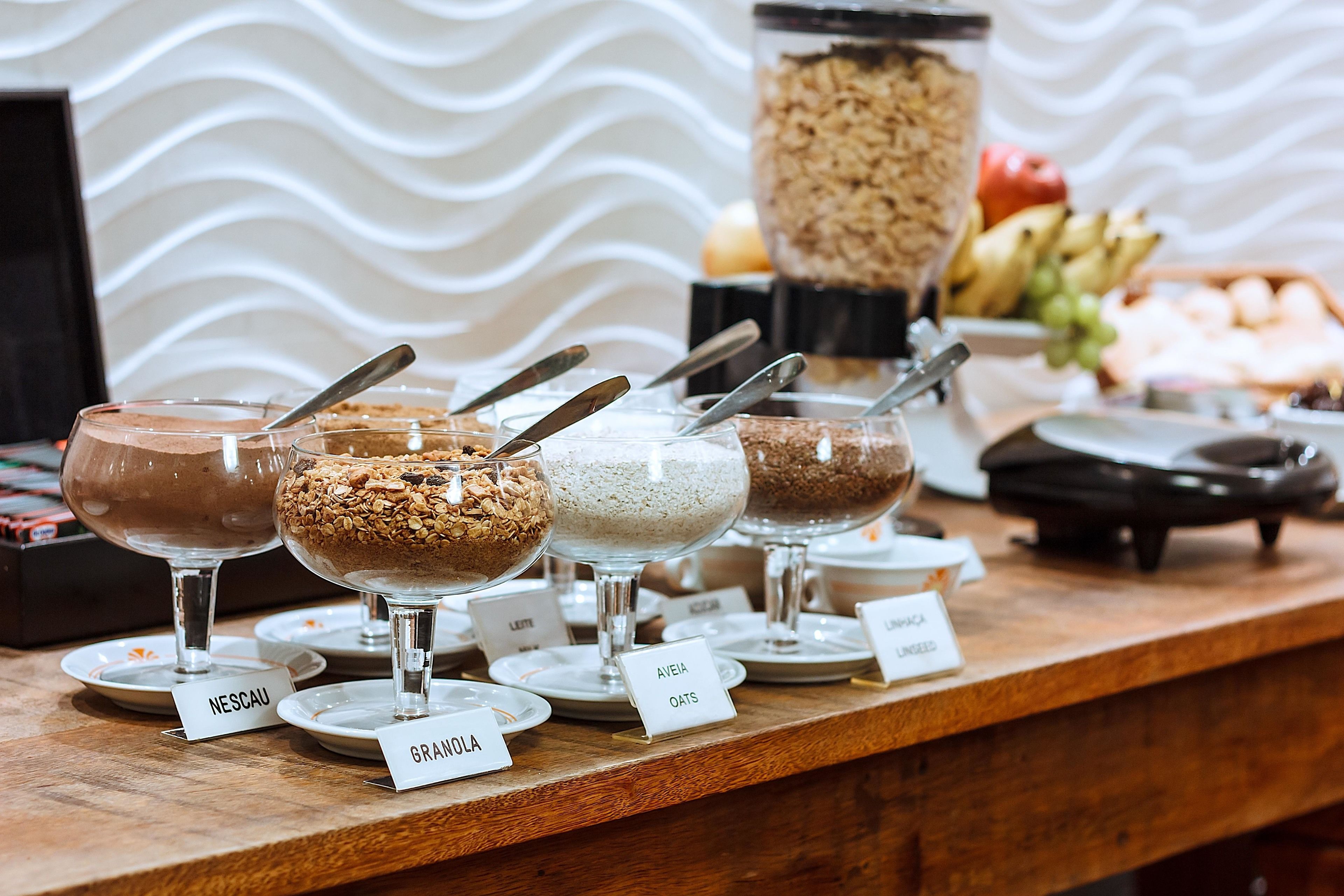 A buffet with labeled dishes of granola, oats, and other breakfast items.