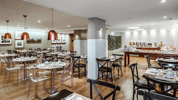 Un comedor moderno con mesas redondas, sillas transparentes e iluminación colgante.