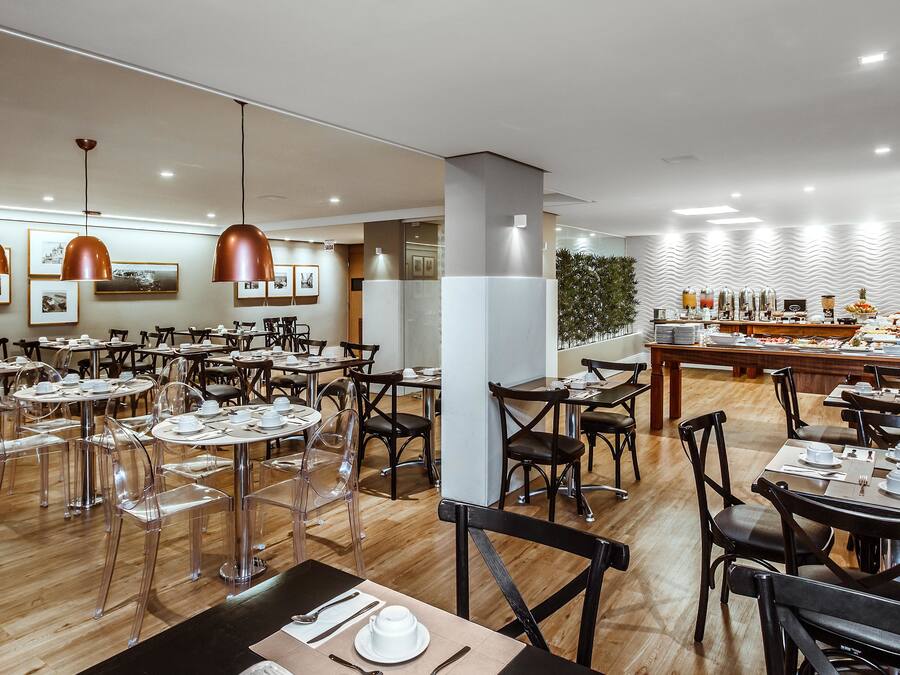 Un comedor moderno con mesas redondas, sillas transparentes e iluminación colgante.