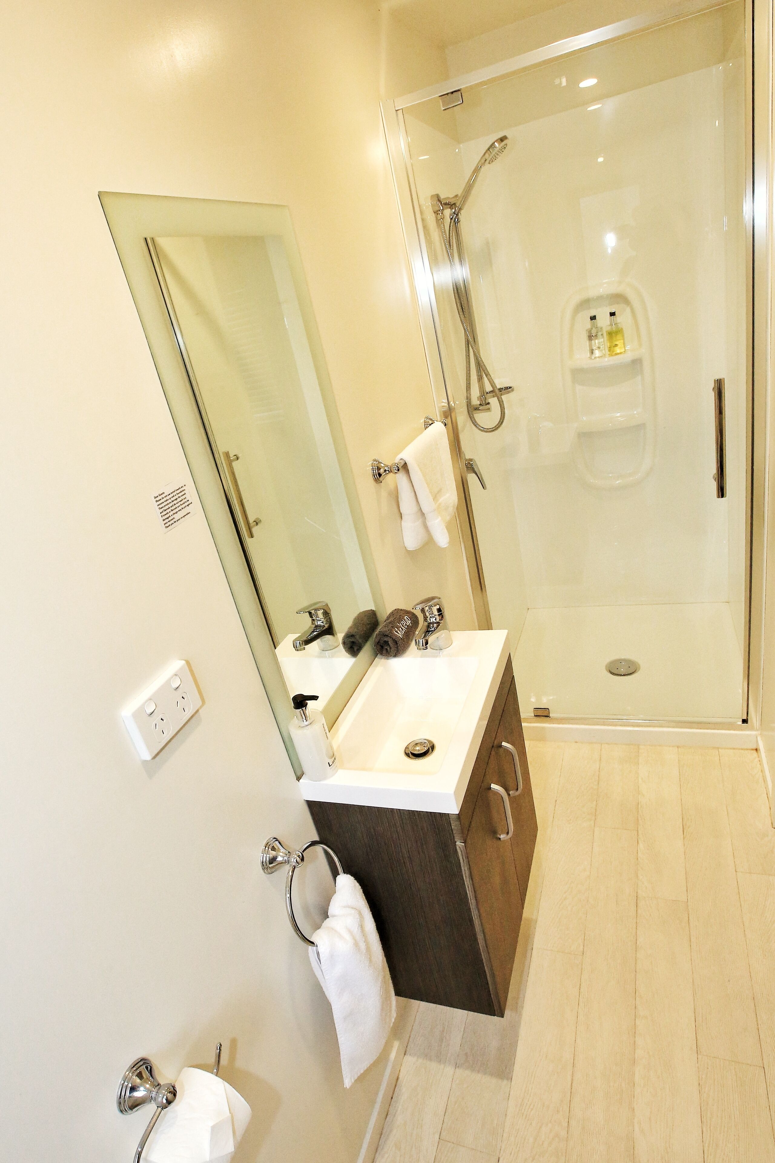 A modern bathroom with a glass-enclosed shower, a vanity with a mirror, and a toilet.