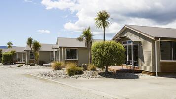 A row of modern, single-story buildings with a flat roof, each featuring a patio area with outdoor seating.