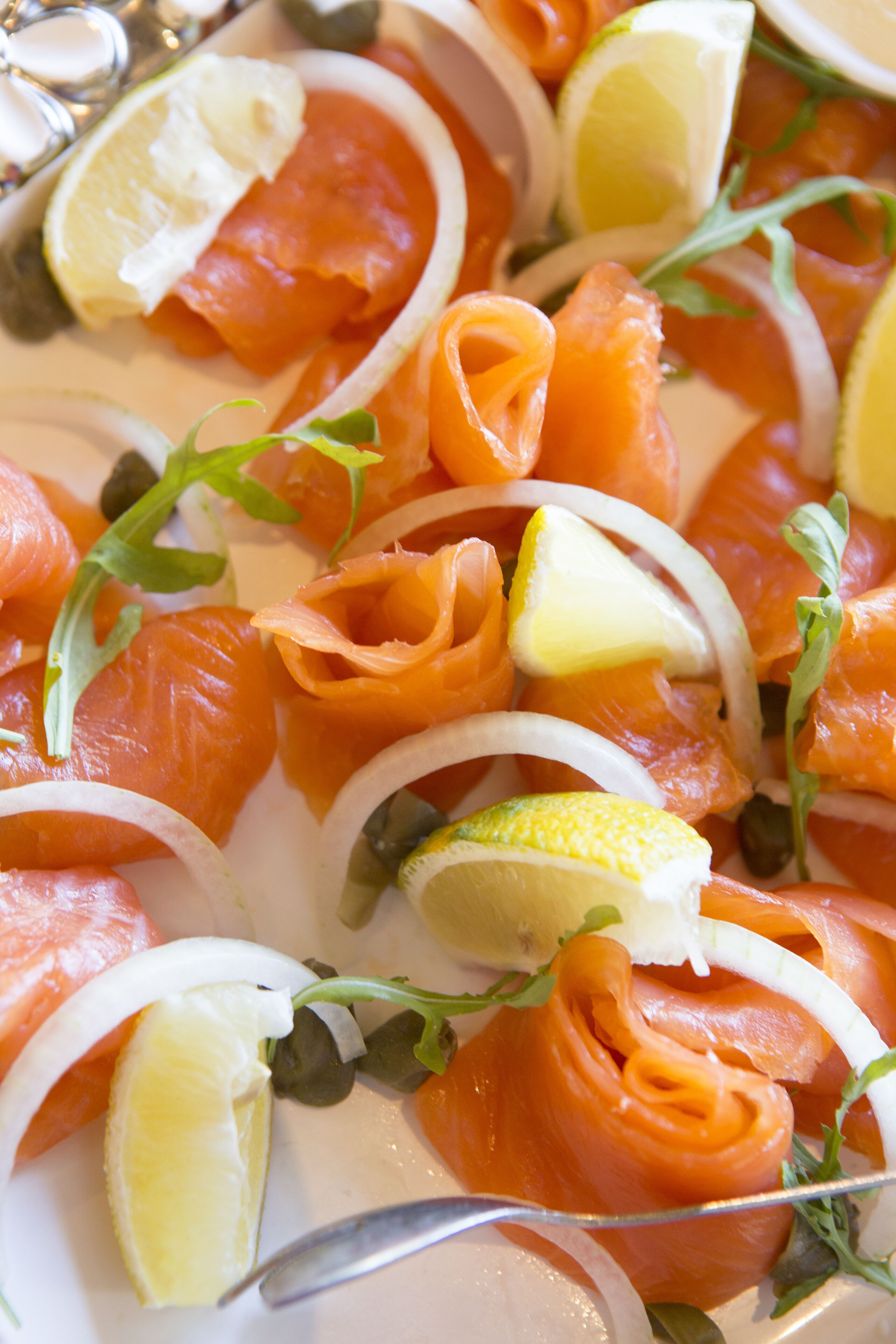 A plate of smoked salmon with lemon slices and capers.