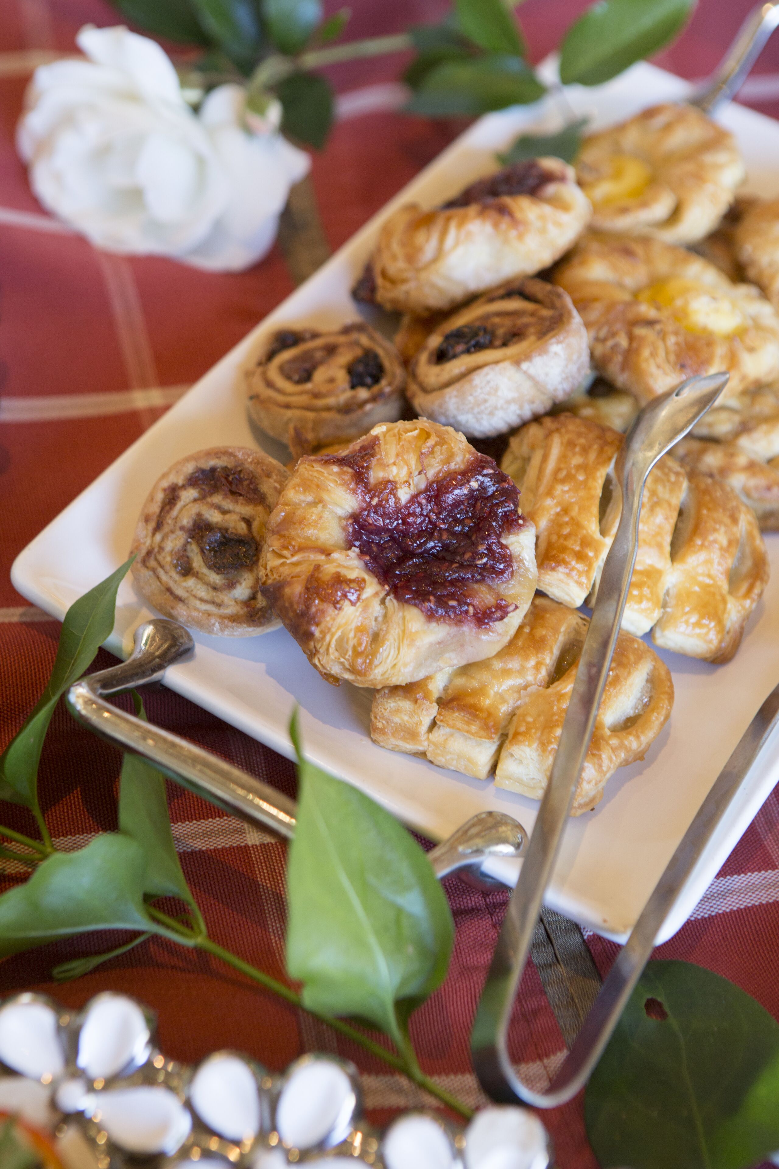 A tray of assorted pastries on a table with a red and white checkered tablecloth.