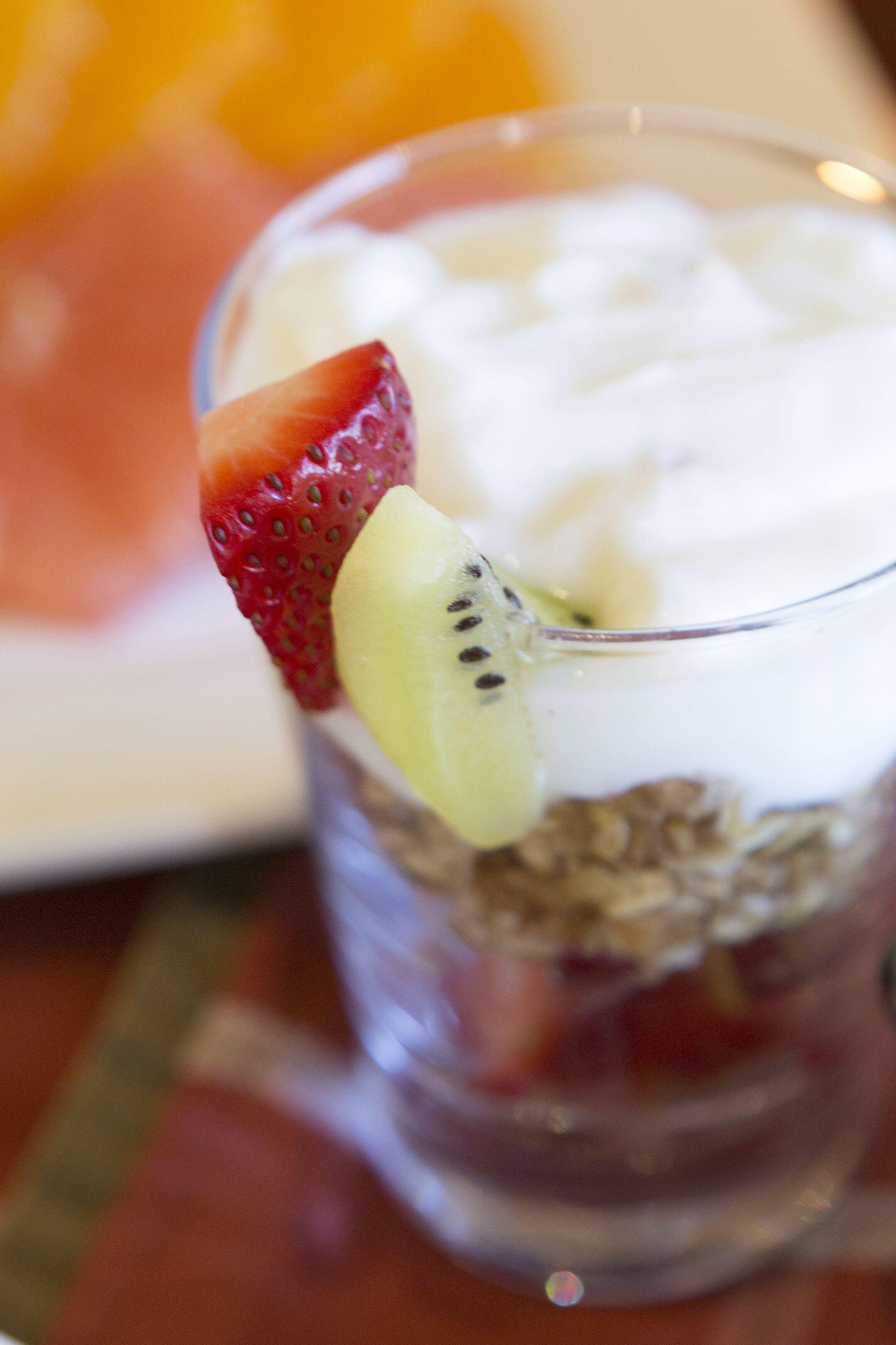 A dessert with a strawberry and kiwi slice on top of a glass.