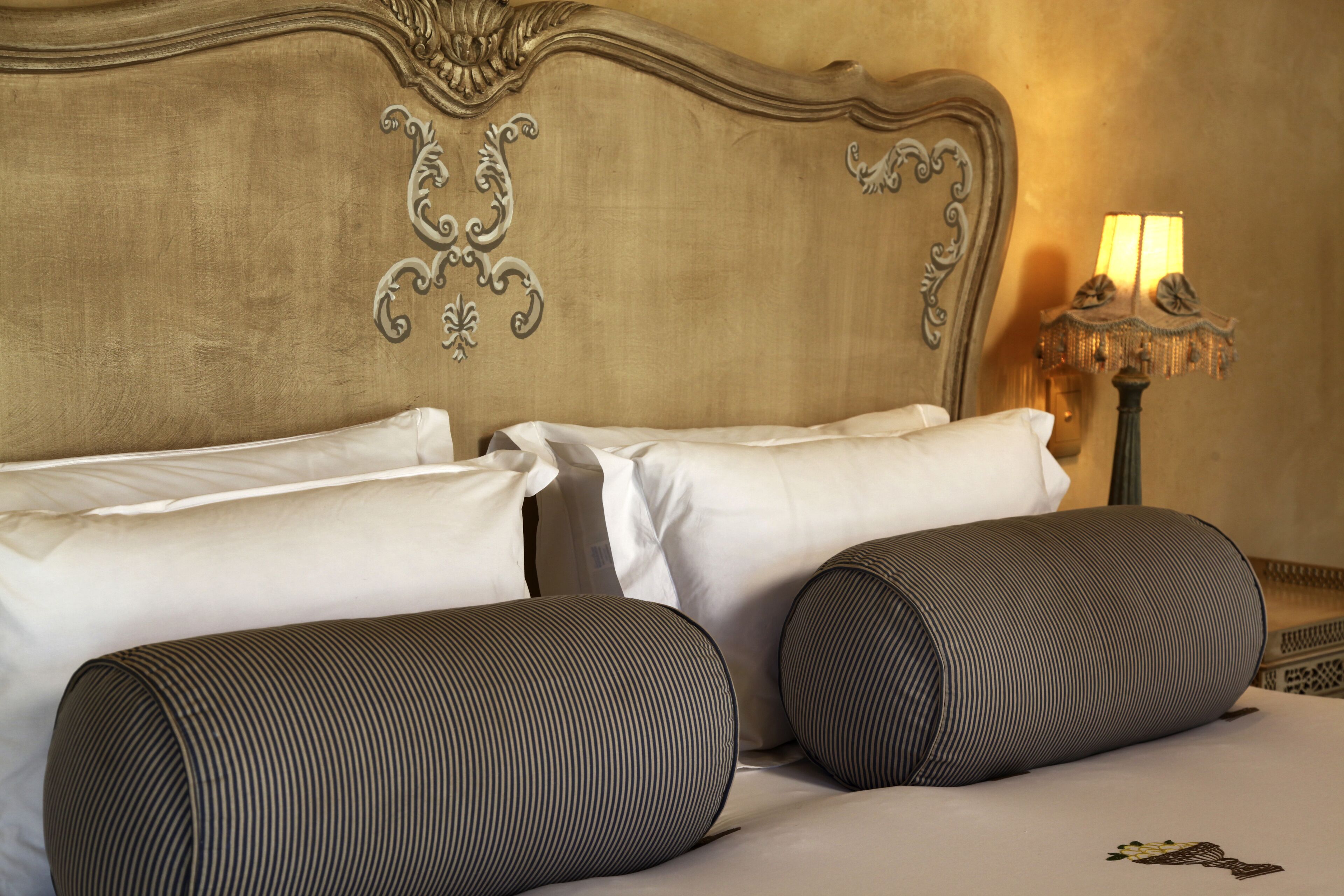 Une chambre d’hôtel avec un grand lit, du linge de lit blanc et une tête de lit décorative.