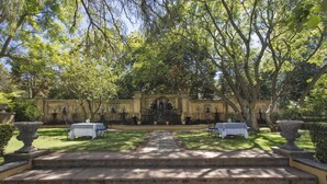 A garden with a fountain, two tables, and steps leading to a building with a balcony. - Franschhoek Country House and Villas (Franschhoek)