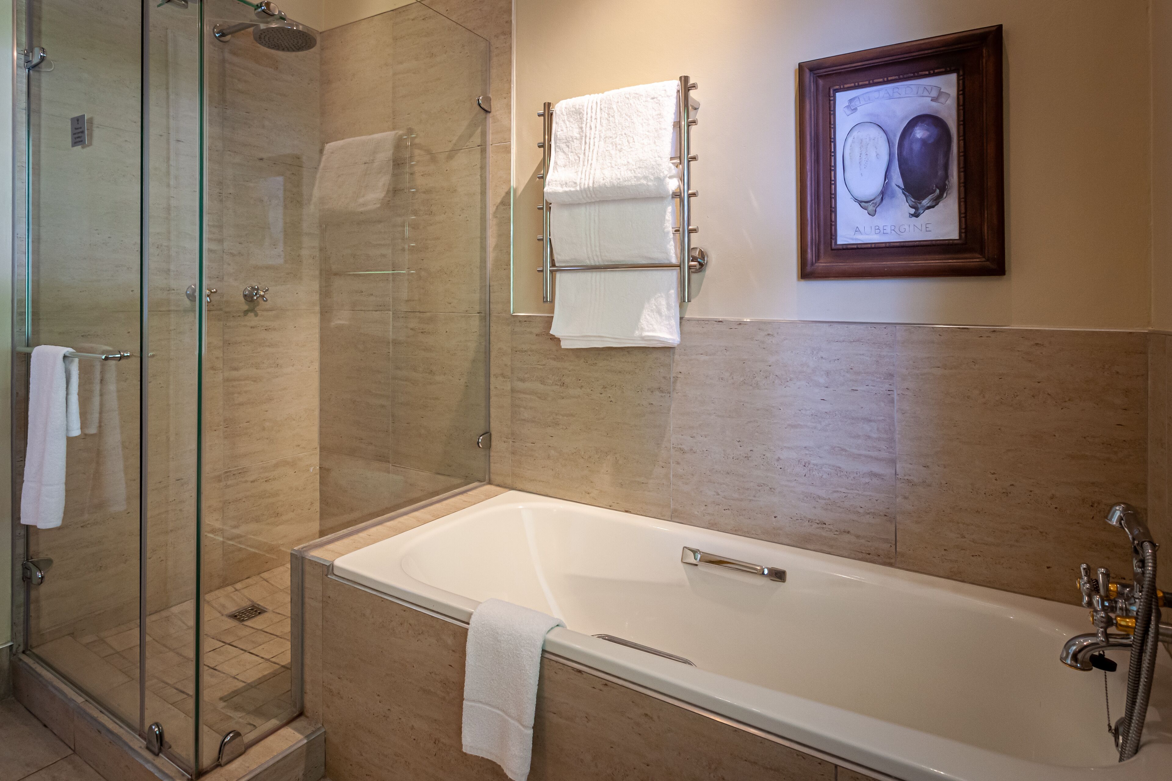 A modern bathroom with a glass-enclosed shower, a large bathtub, and a framed picture on the wall.