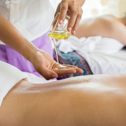 A massage therapy session with a person receiving a massage on a bed.
