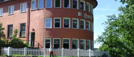 A red building with multiple windows and a sign that reads "Hotel."