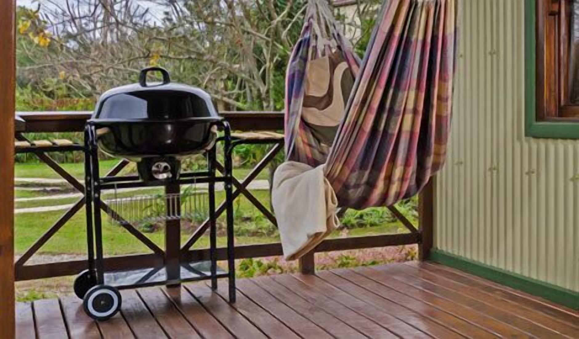 Una terraza de madera con una parrilla y una hamaca.